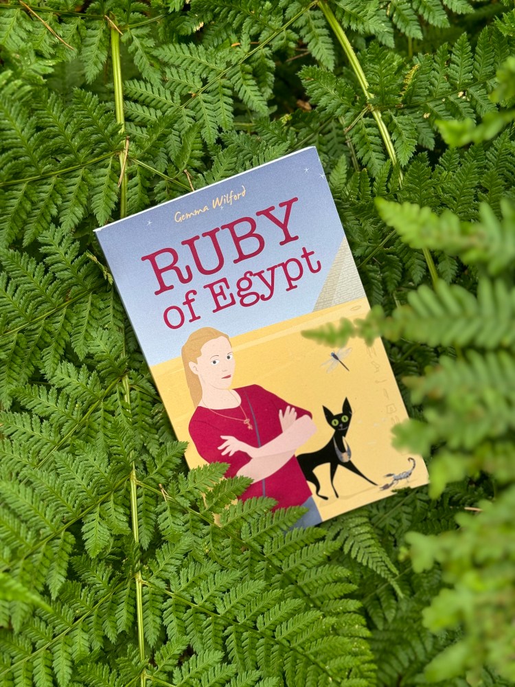 Book cover for Ruby of Egypt. Teenage girl standing near a pyramid in the desert with a black cat standing behind her.