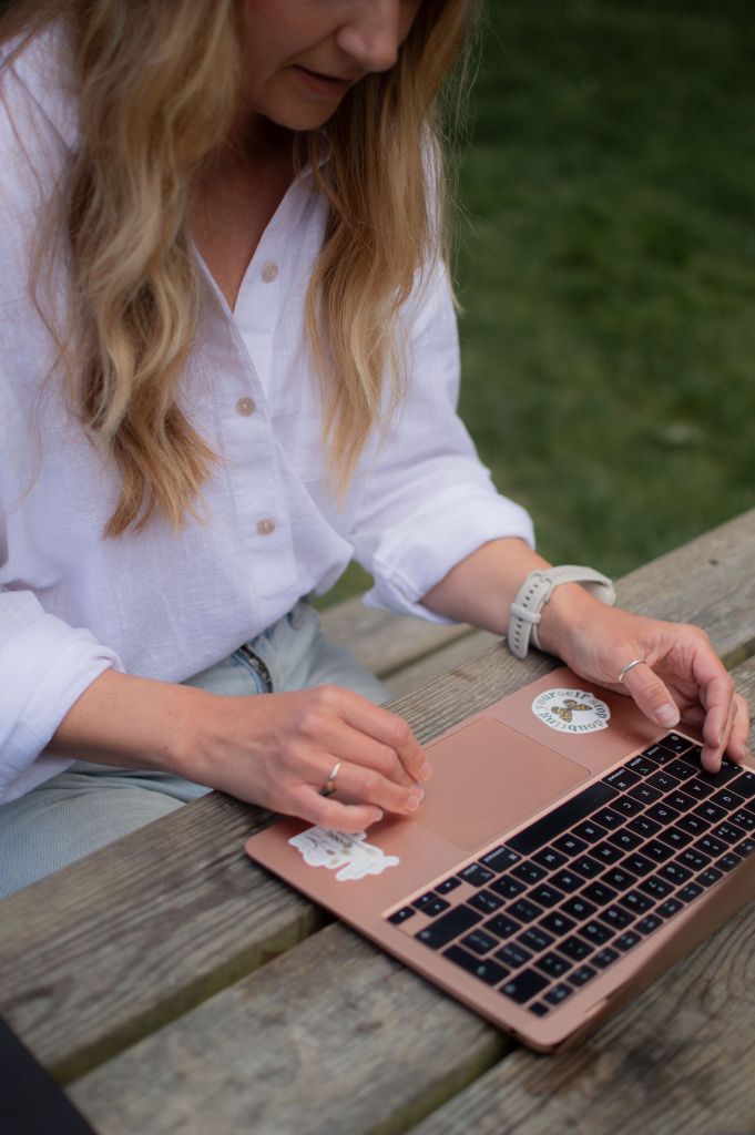 Woman sitting at picnic table typing on a laptop